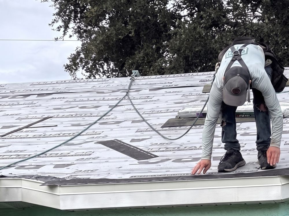 A roofer in an SFR shirt and harness setting the starter course at the eave over new underlayment