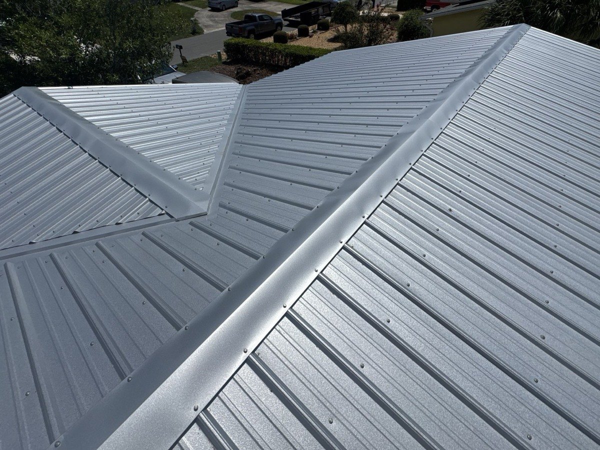A finished exposed fastener metal roof with ribbed panels, a hip and a valley