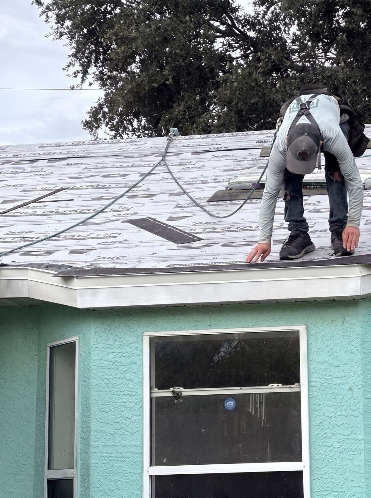 A crew member in his SFR shirt setting the starter course at the eave over the new underlayment on a shingle roof in Ocala