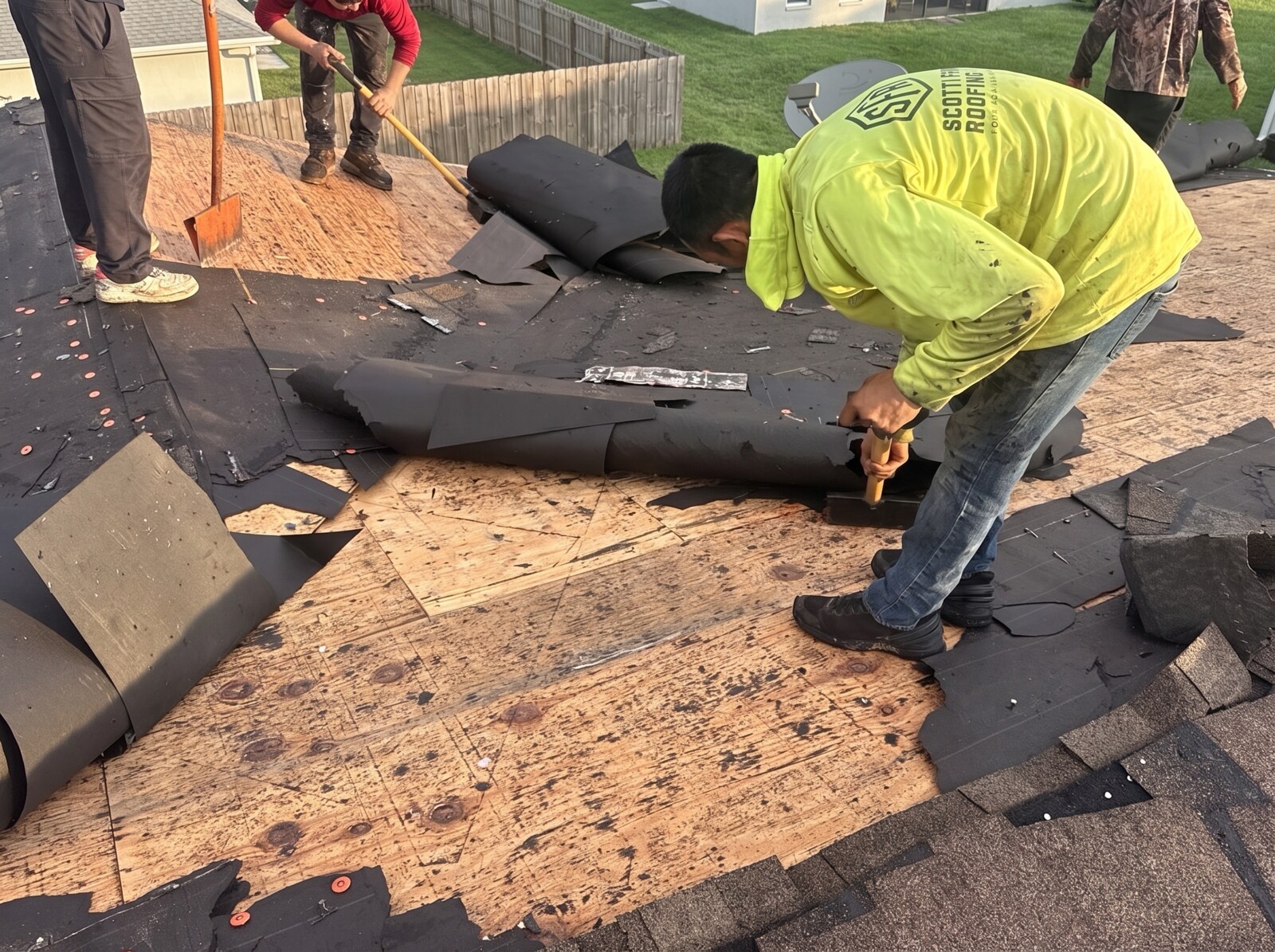 Roofer stripping old shingles with a pry bar during a Beverly Hills FL tear off