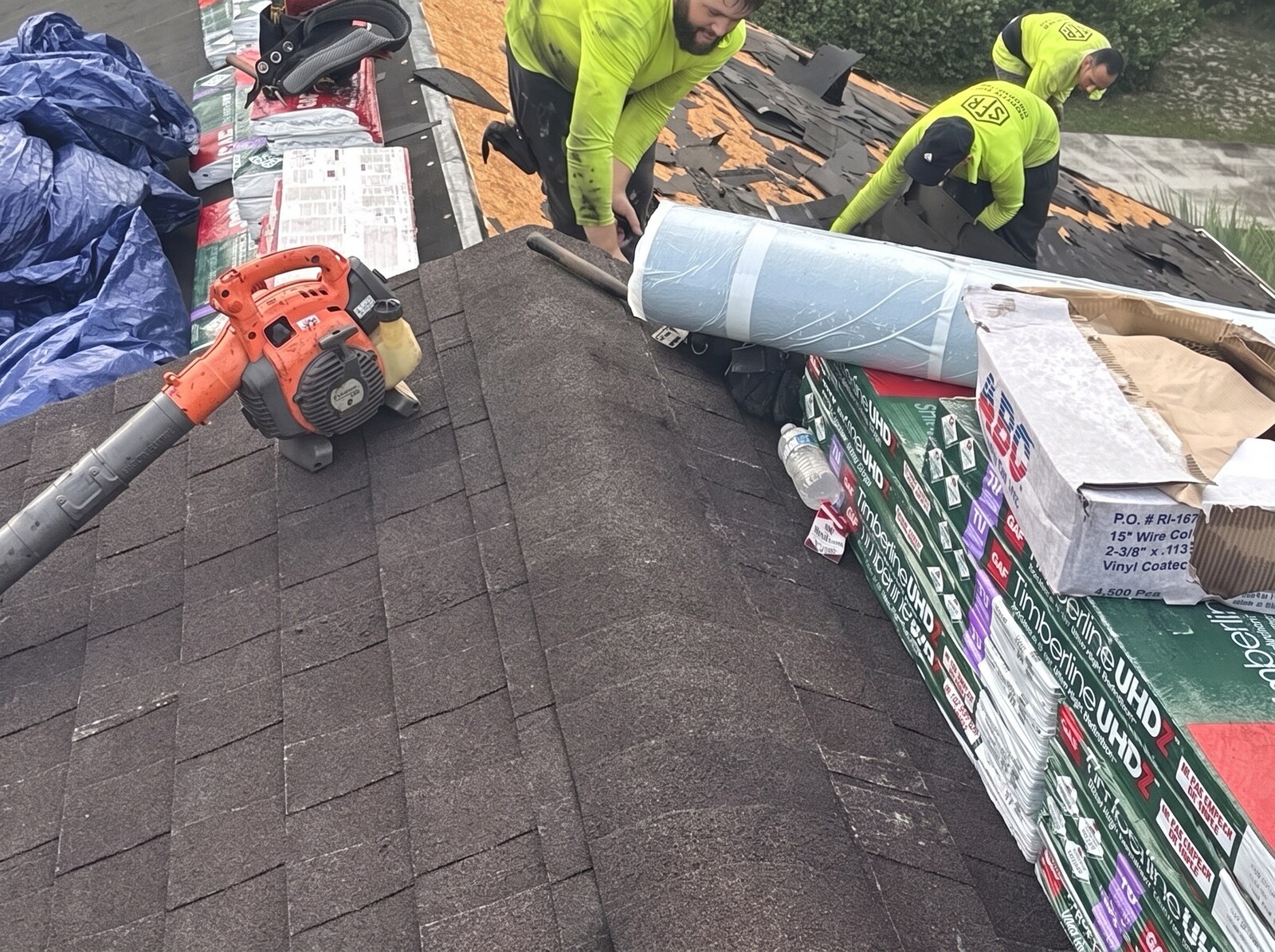 Two Scotti Family Roofing crew members rolling peel and stick underlayment on a Hernando FL roof deck