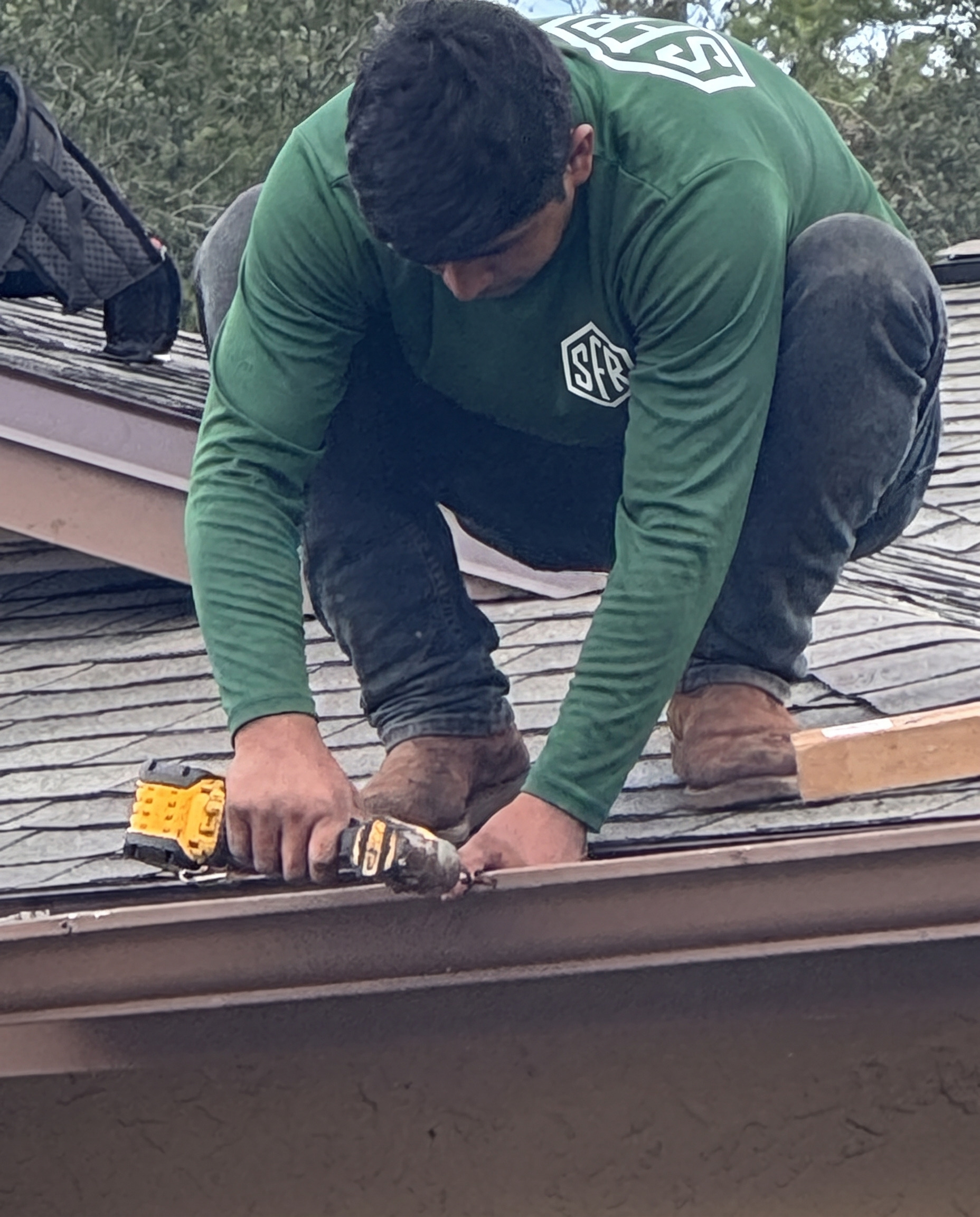 Roofer fastening galvanized drip edge with a nail gun on a Tampa FL reroof