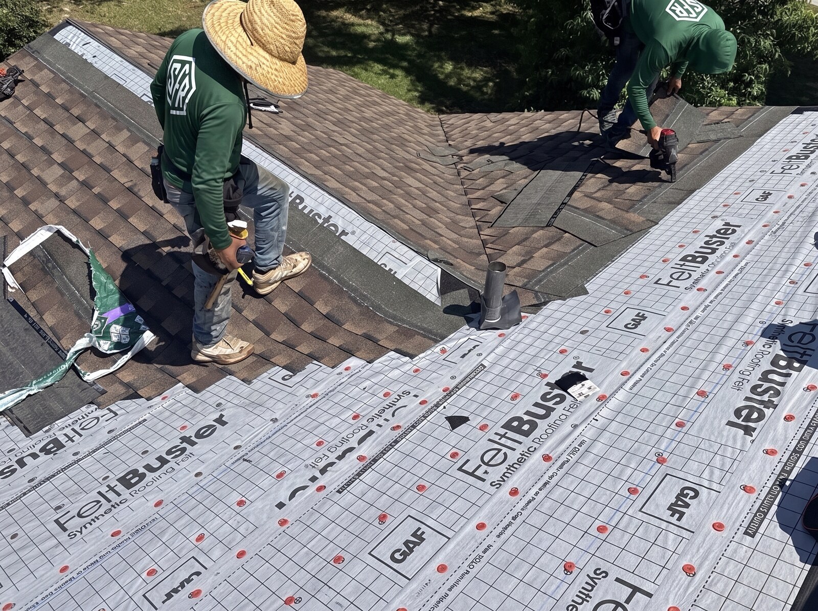 Two Scotti Family Roofing crew members laying shingle courses on a Spring Hill FL roof