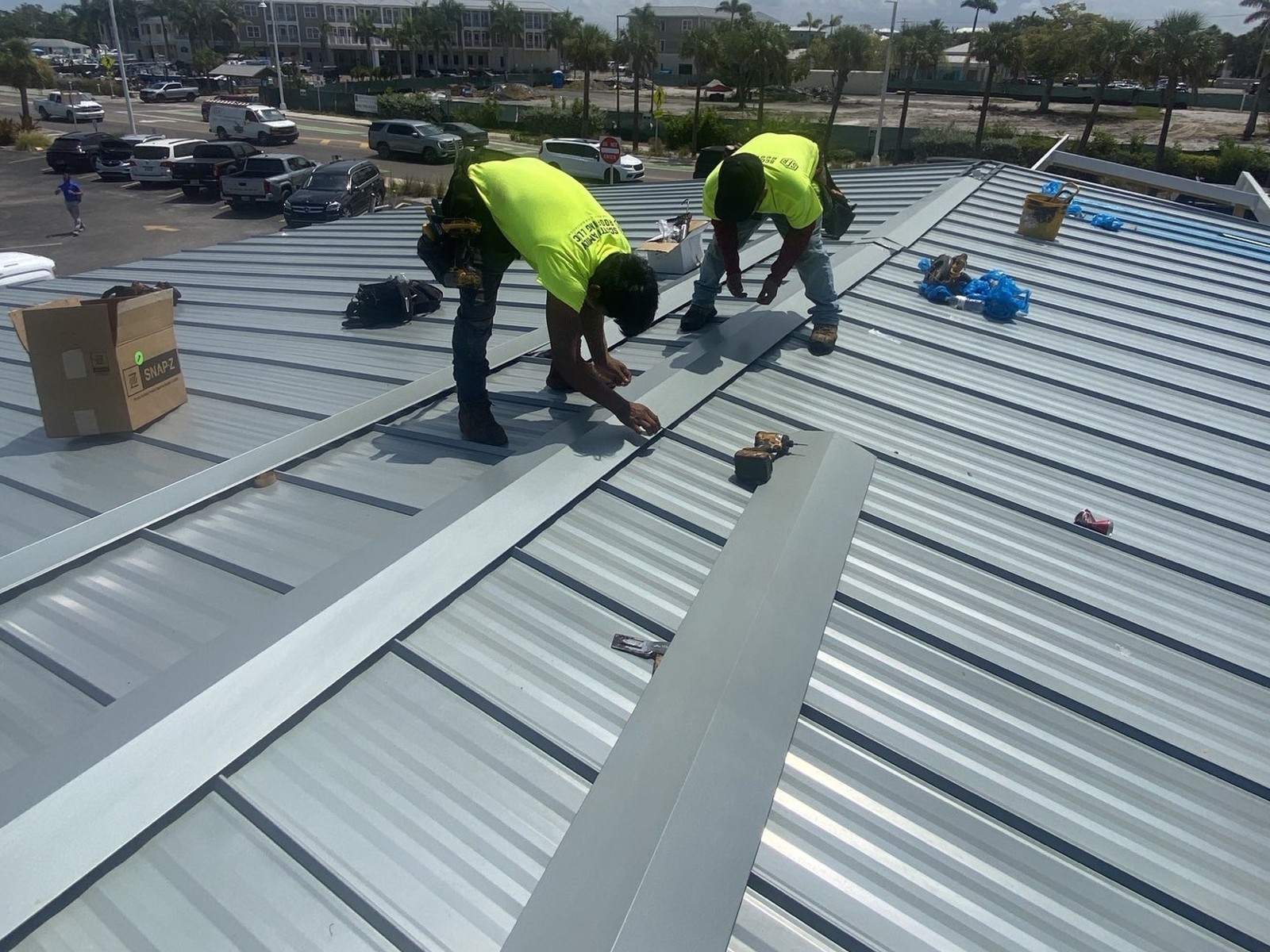 Roofing crew fastening metal panels on a Holmes Beach FL commercial roof