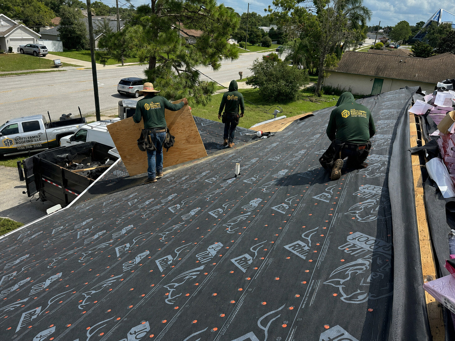 Scotti Family Roofing crew in branded shirts installing RhinoRoof underlayment on a Spring Hill FL roof