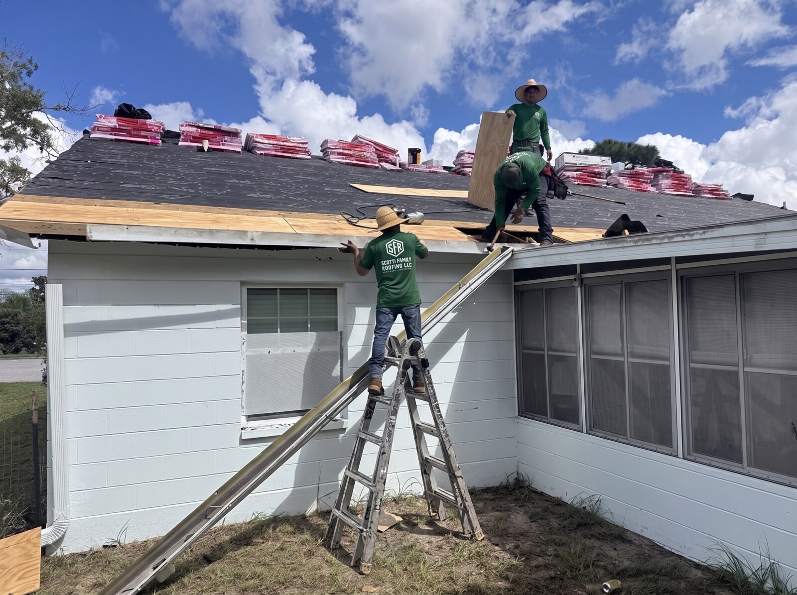 Roofer carrying replacement decking up the ladder on a Spring Hill FL roof replacement