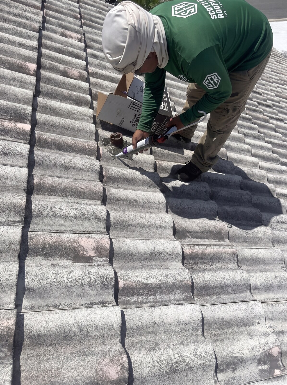 Roofer applying sealant while resetting concrete tile on a Weeki Wachee FL roof